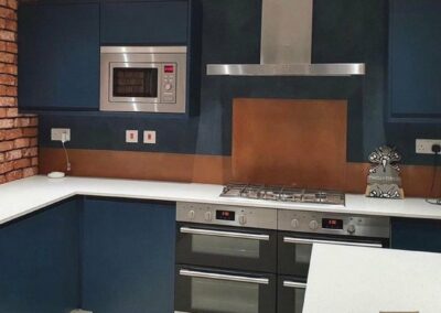 orange burnished splashback in blue modern kitchen