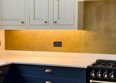 gold brass splashback in white and blue kitchen