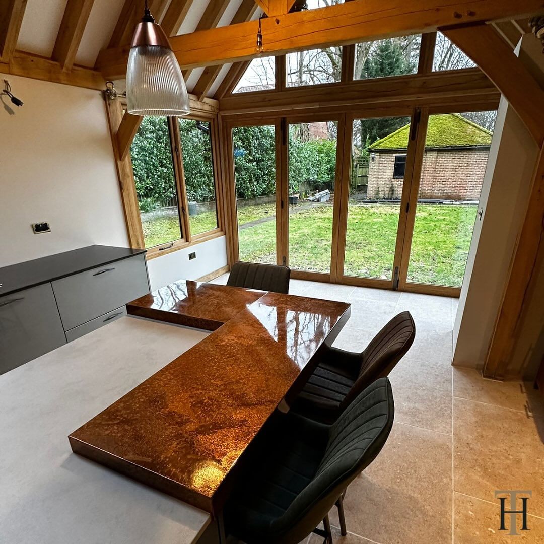 A kitchen featuring aged copper countertops in the centre with large windows in the background