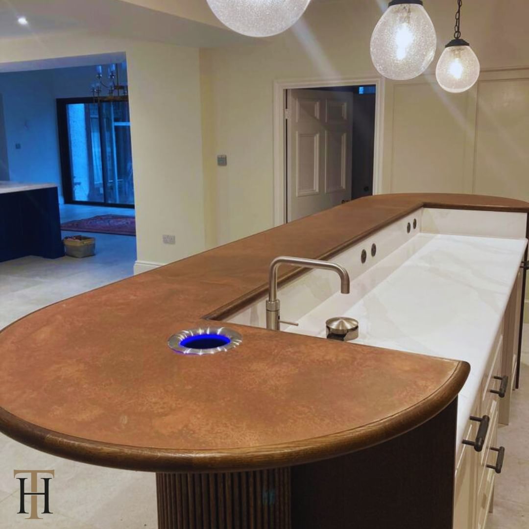 Custom-made kitchen island with an aged copper table top and wooden border.