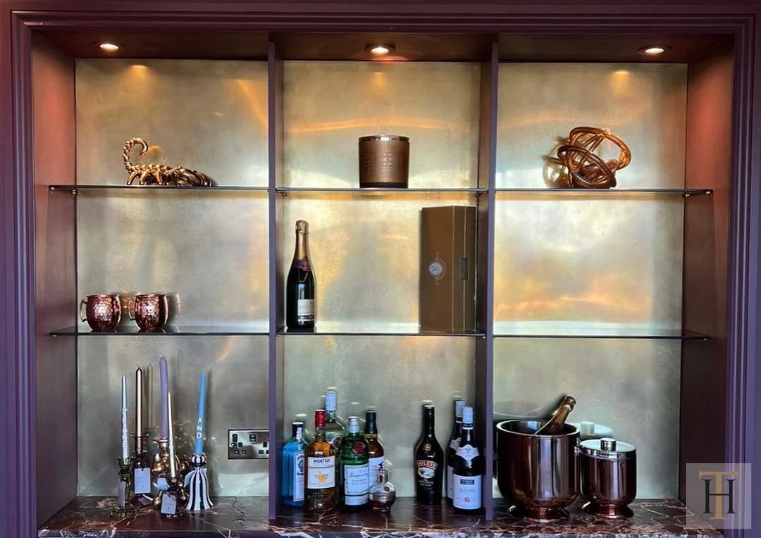 Home bar with glass shelves and a Berkshire Bronzed brass panel as the backdrop.